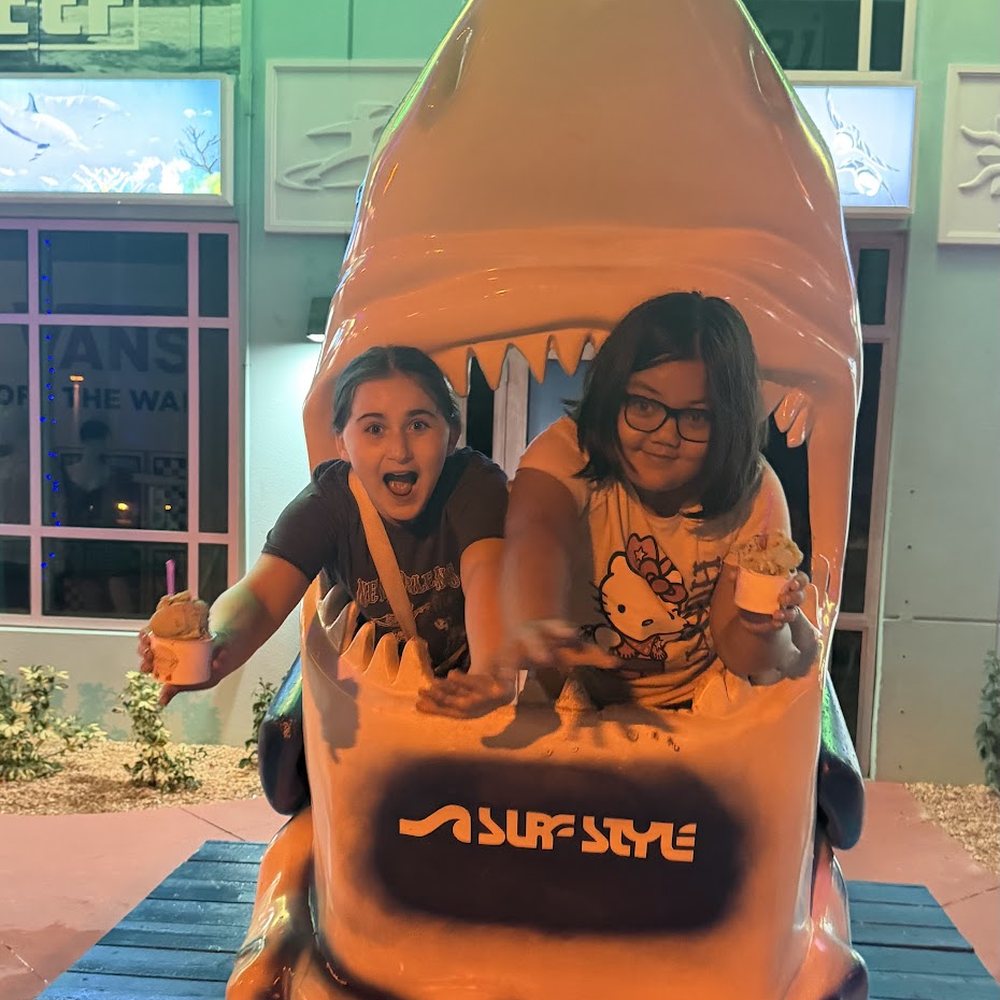 Lincoln and a friend posing inside a large shark statue with ice cream